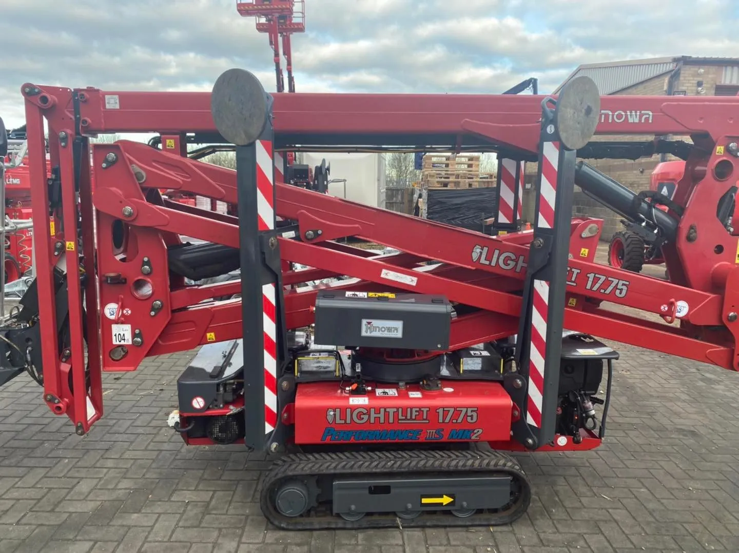 A large red machine parked on top of a brick road.
