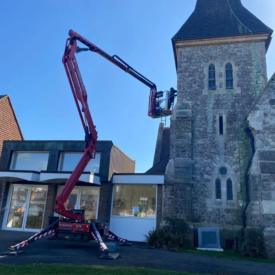 A man on a cherry picker in front of a church.